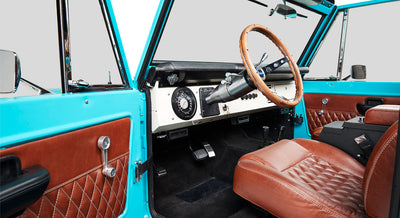Classic Ford Bronco pedals and footwell area with black carpeting and silver accelerator pedal