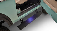 Classic Ford Bronco door open revealing black power step and part of turquoise body