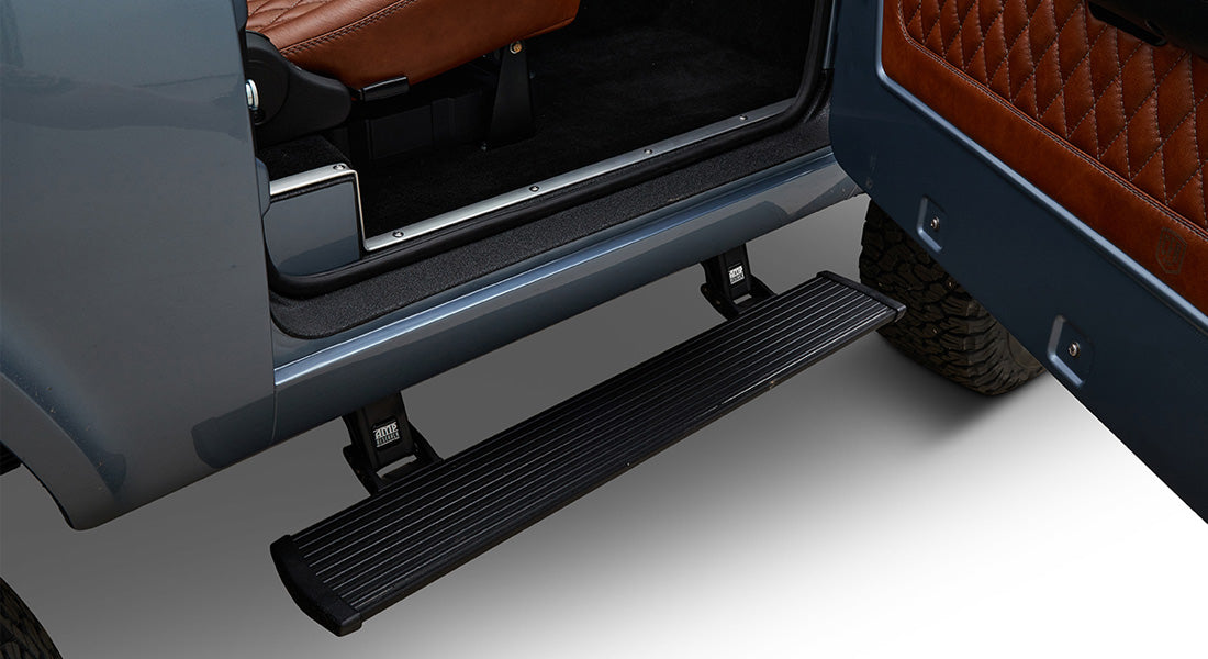 Retracted black powerstep attached to the side under the door of a Classic Ford Bronco