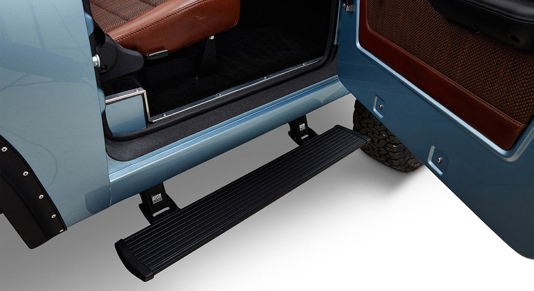 Black power step extended beneath open door of light blue Classic Ford Bronco