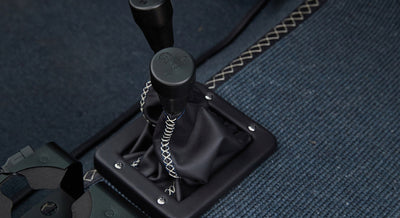 Two black gear shift levers with leather boot and contrast stitching on Classic Ford Bronco floor