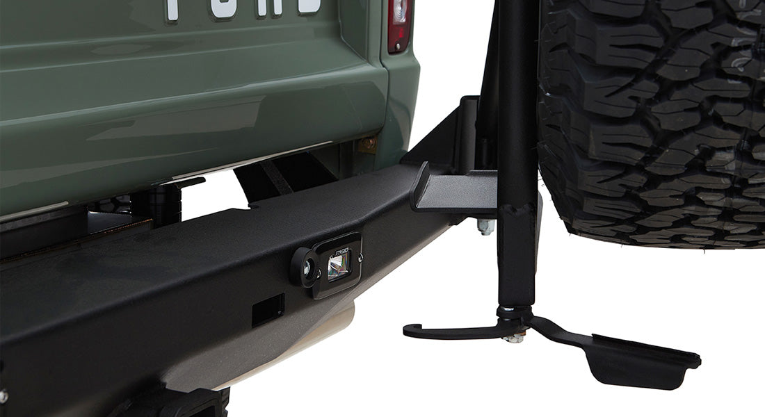 Black steel spare tire carrier mounted on green Classic Ford Bronco with large off-road tire