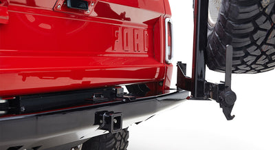 Rear side of red Classic Ford Bronco with black metal spare tire carrier and hitch receiver
