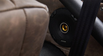 Black round speaker with yellow center behind brown leather seat back