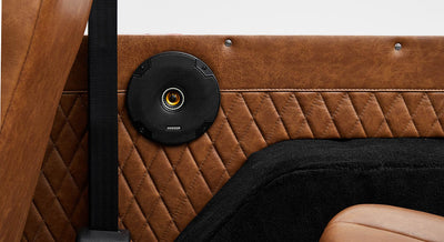 Black circular speaker mounted on diamond-stitched brown leather interior panel of Classic Ford Bronco
