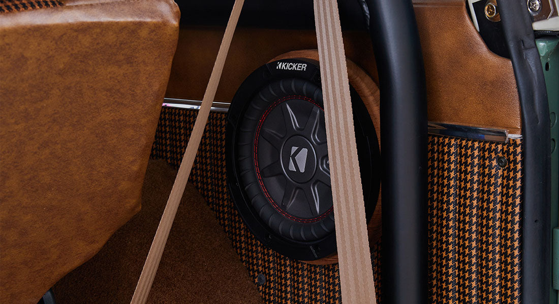 Classic Ford Bronco interior showing a black and red Kicker speaker with seatbelt straps