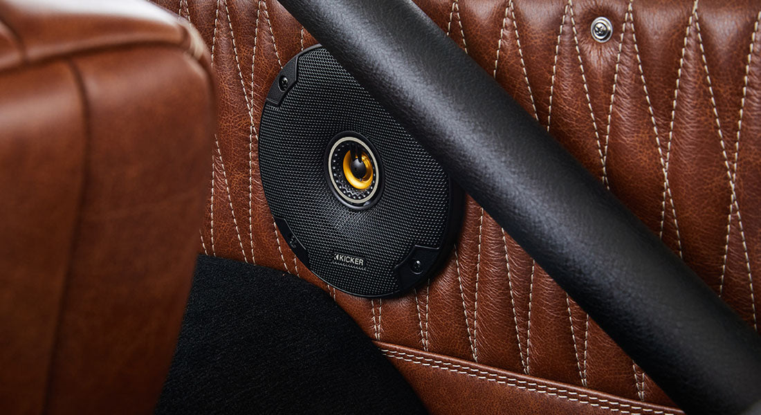 Black speaker installed in a brown leather door panel inside a Classic Ford Bronco