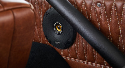 Black speaker installed in a brown leather door panel inside a Classic Ford Bronco