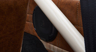 Close-up of black speaker mounted on brown leather interior panel with roll cage in Classic Ford Bronco