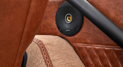 Kicker speaker mounted on brown leather door panel inside a Classic Ford Bronco