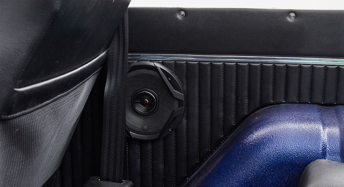 Black audio speaker mounted on black interior panel with blue wheel well in Classic Ford Bronco