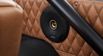 Black Kicker speaker mounted on quilted brown leather interior panel