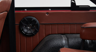Black round speaker mounted on brown leather interior panel of a Classic Ford Bronco