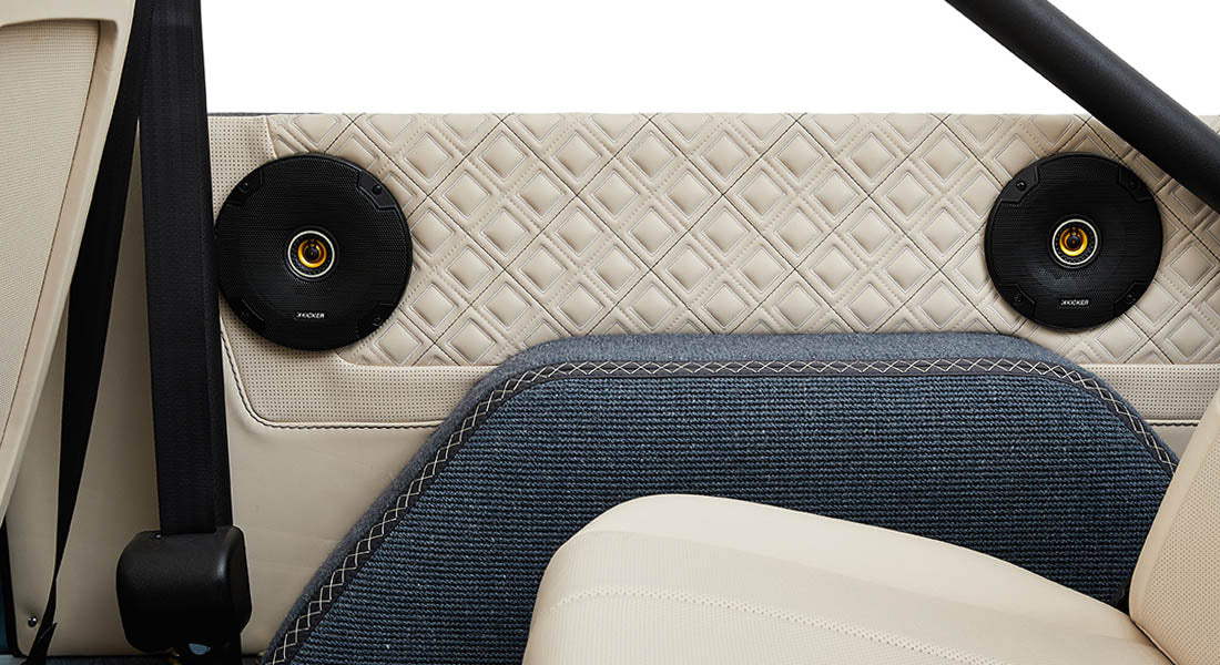 Interior rear side panel of Classic Ford Bronco with two black speakers and blue carpet