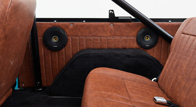 Two black round speakers mounted on brown leather interior panel of Classic Ford Bronco