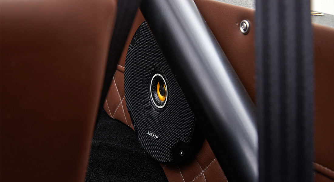 Close-up of black speaker mounted on brown leather diamond-stitched panel inside Classic Ford Bronco.