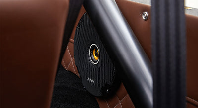 Close-up of black speaker mounted on brown leather diamond-stitched panel inside Classic Ford Bronco.