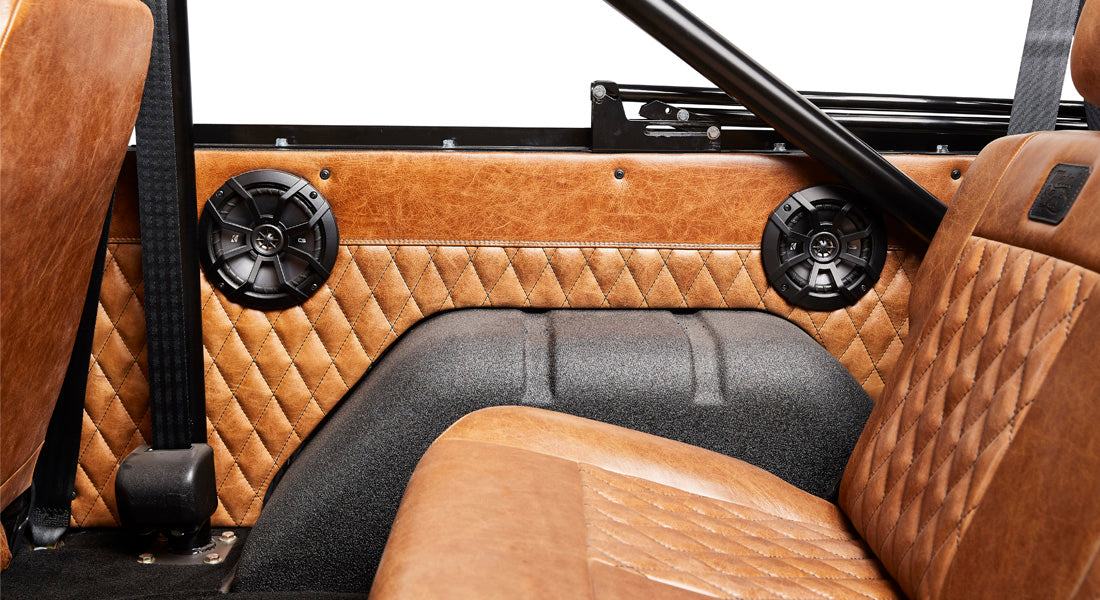 Brown quilted panel inside Classic Ford Bronco with black speaker grilles and brown leather seats