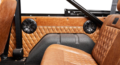 Brown quilted panel inside Classic Ford Bronco with black speaker grilles and brown leather seats