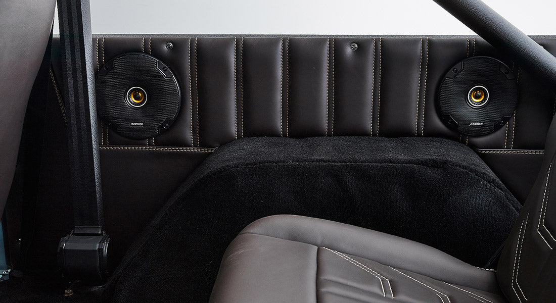 Rear interior side panel of Classic Ford Bronco showing speakers, seatbelt, and black upholstery