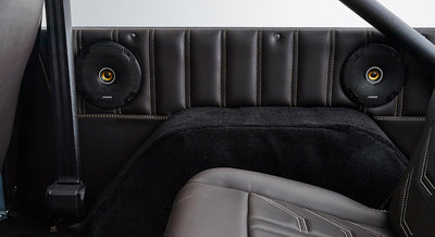Rear interior side panel of Classic Ford Bronco showing speakers, seatbelt, and black upholstery