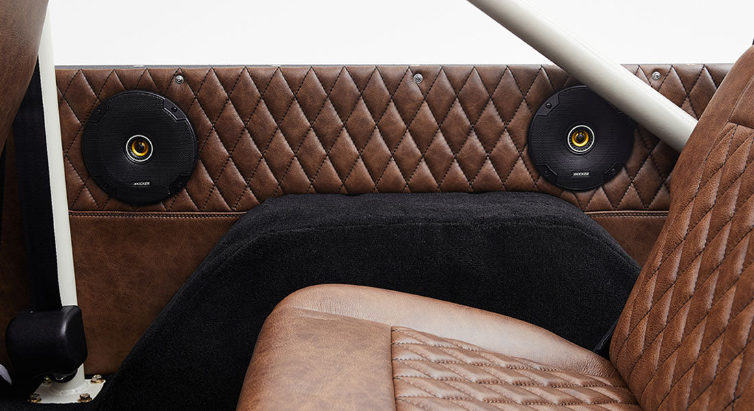 Brown leather interior with two round black speakers mounted on quilted panels