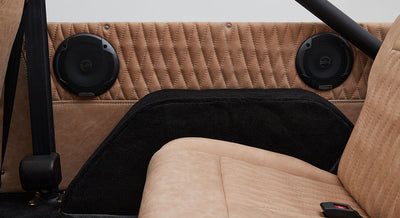 Tan quilted upholstery with black speaker grills and part of a seatback in a Classic Ford Bronco