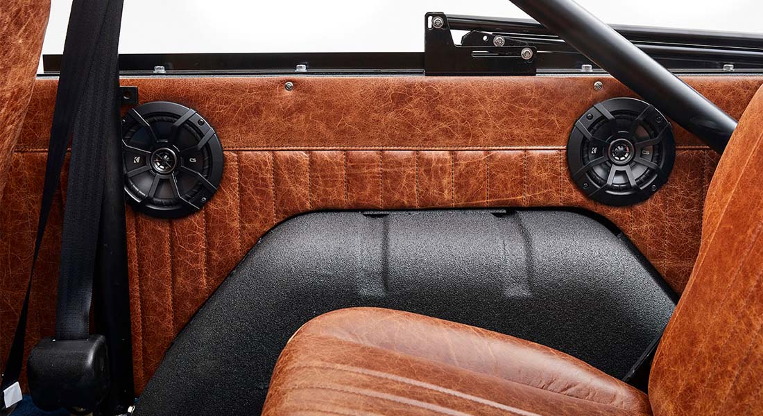 Interior side panel with black speakers and brown leather upholstery in Classic Ford Bronco