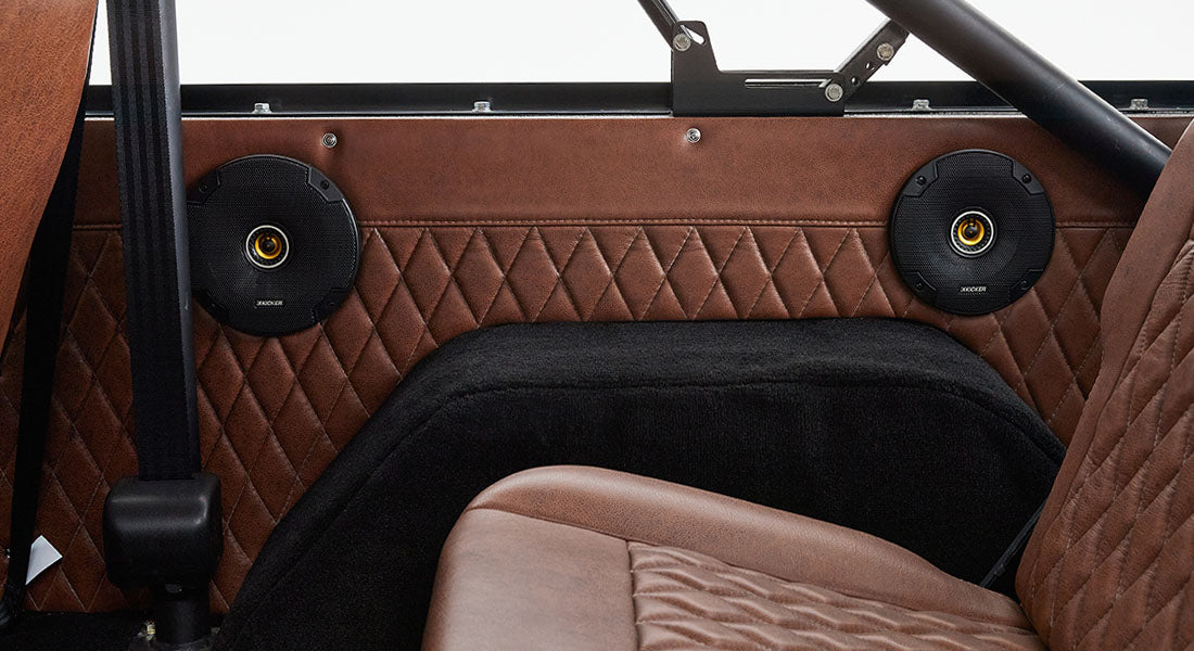 Interior side panel of Classic Ford Bronco with brown leather, diamond stitching, and two speakers