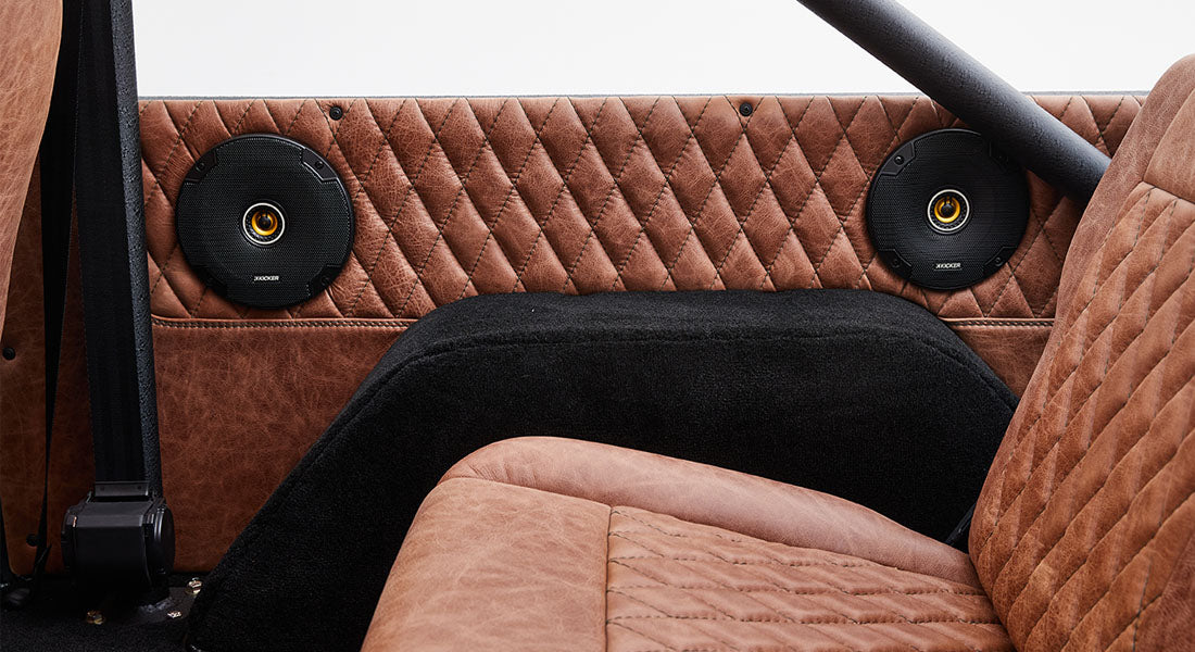 Two round speakers set in quilted brown leather door panel inside Classic Ford Bronco