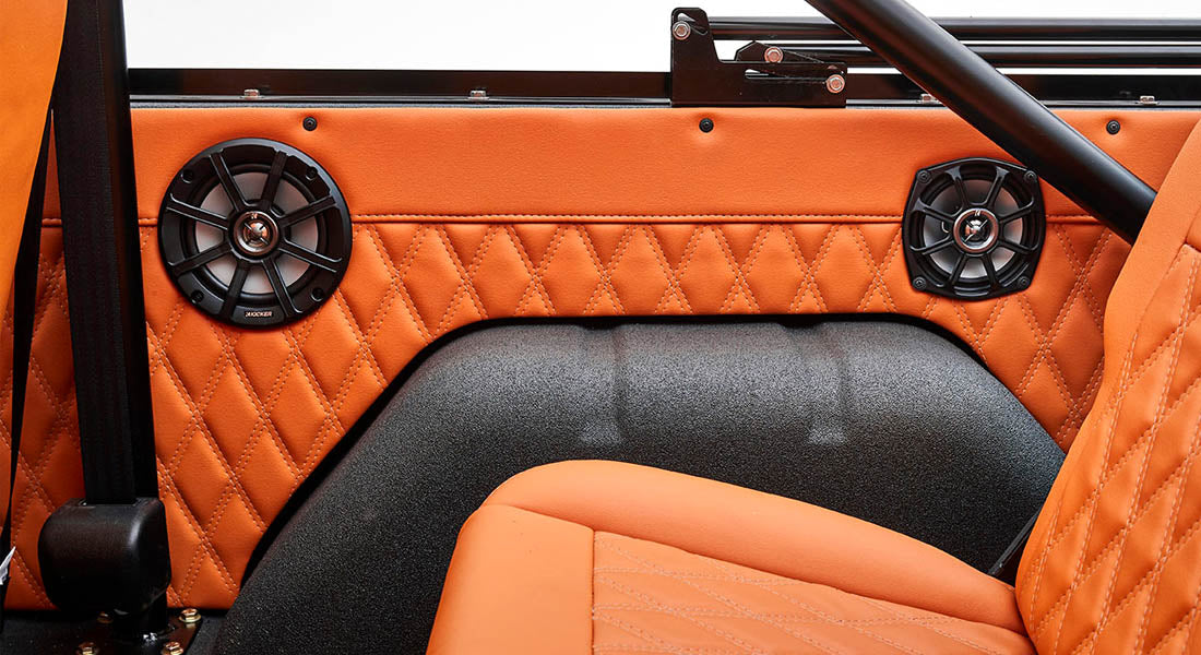 Orange quilted door panel with mounted black speakers inside Classic Ford Bronco