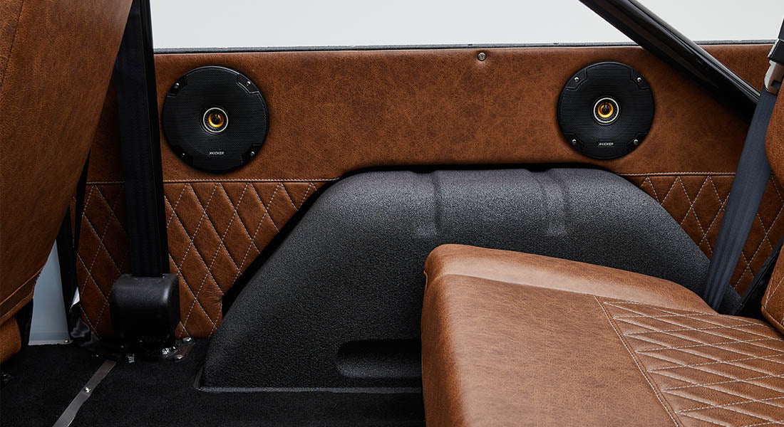 Rear interior side panel with two black round speakers and brown leather upholstery inside Classic Ford Bronco