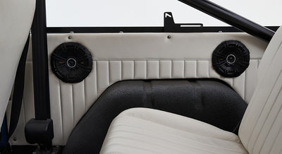Two black round speakers mounted on white Classic Ford Bronco interior panel