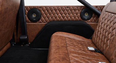 Brown leather back seat and two round black speakers inside Classic Ford Bronco