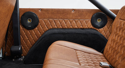 Two black speakers mounted on brown quilted leather interior panel of Classic Ford Bronco