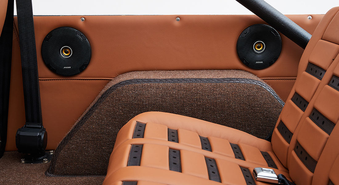 Two round black speakers mounted on tan panel behind rear seats of Classic Ford Bronco