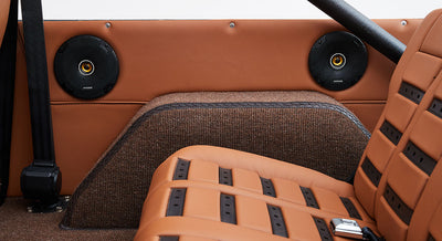 Two round black speakers mounted on tan panel behind rear seats of Classic Ford Bronco