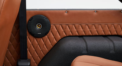 Black speaker mounted on tan diamond-stitched leather panel inside Classic Ford Bronco