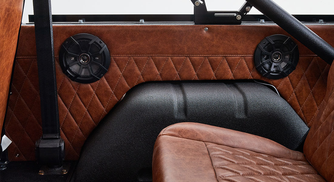 Brown leather interior door panel with two black speakers and black roll cage