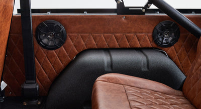 Brown leather interior door panel with two black speakers and black roll cage