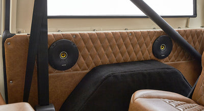 Rear interior panel with brown diamond-stitched leather and two black speakers in Classic Ford Bronco