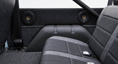 Classic Ford Bronco rear interior with black upholstery and two black round speakers on side panels.