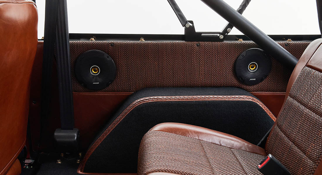 Classic Ford Bronco rear interior with brown leather panels, speakers, and woven fabric seats