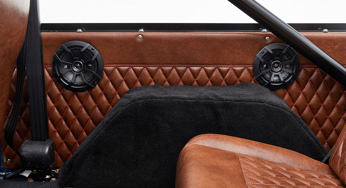 Black speakers mounted on quilted brown leather upholstery inside Classic Ford Bronco