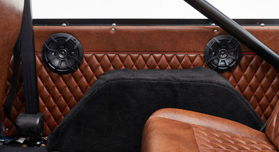 Black speakers mounted on quilted brown leather upholstery inside Classic Ford Bronco