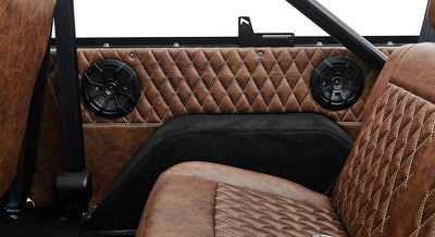 Rear seating area with black speakers and brown leather upholstery inside Classic Ford Bronco