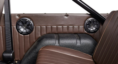 Interior side panel of a Classic Ford Bronco with two black round speakers and brown upholstery.