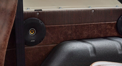 Black speaker mounted on dark brown leather panel inside Classic Ford Bronco