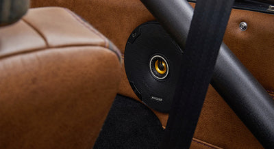 Kicker brand speaker installed in brown leather door panel of Classic Ford Bronco interior