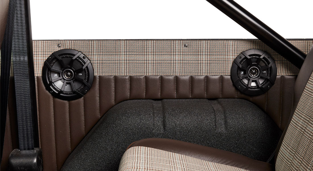 Classic Ford Bronco interior door panel with attached round black speakers and plaid upholstery